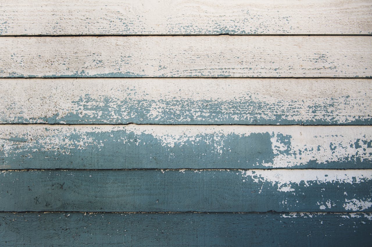A detailed image of a rustic wooden wall with peeling paint, showcasing a vintage texture ideal for design projects.